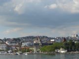 Centrum Lausanne pohledem z vod Ženevského jezera, vlevo věžička zámku Ouchy, zhruba uprostřed je slabě rozeznatelné nádraží, 26.6.2014 © Jan Přikryl