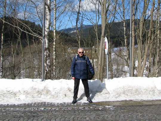 Autor stojící na hraniční čáře, vyznačené před nádražím dlažbou, pravou nohou v SRN, levou v ČR © Helena Bažantová