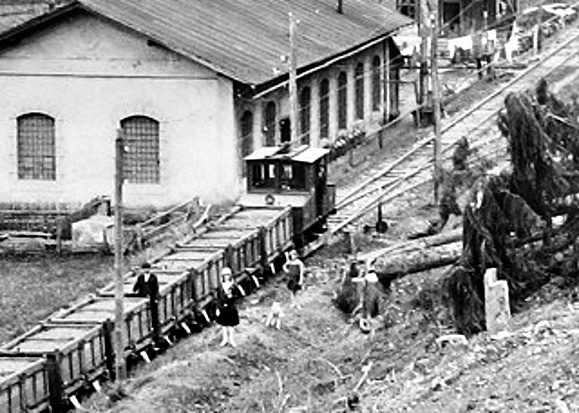 Lokomotíva AEG (smerujúca do Bindtu) odfotená s vozňami pri akumulátorovni v Markušovskej doline počas prevádzky v roku 1925 (ŠUBA Banská Štiavnica)